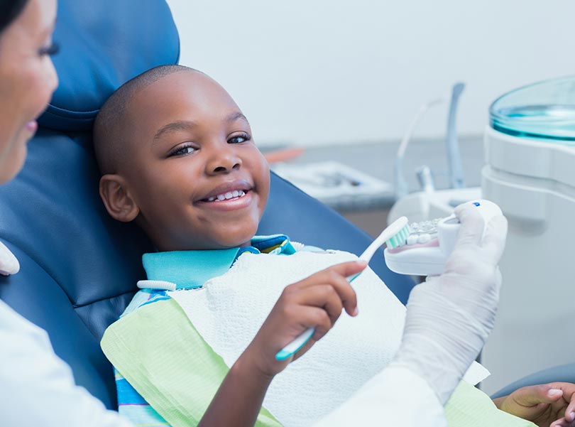 Dentist is teaching dental cleaning to a boy
